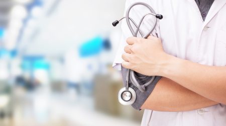 Doctor with a stethoscope in the hands and hospital background.